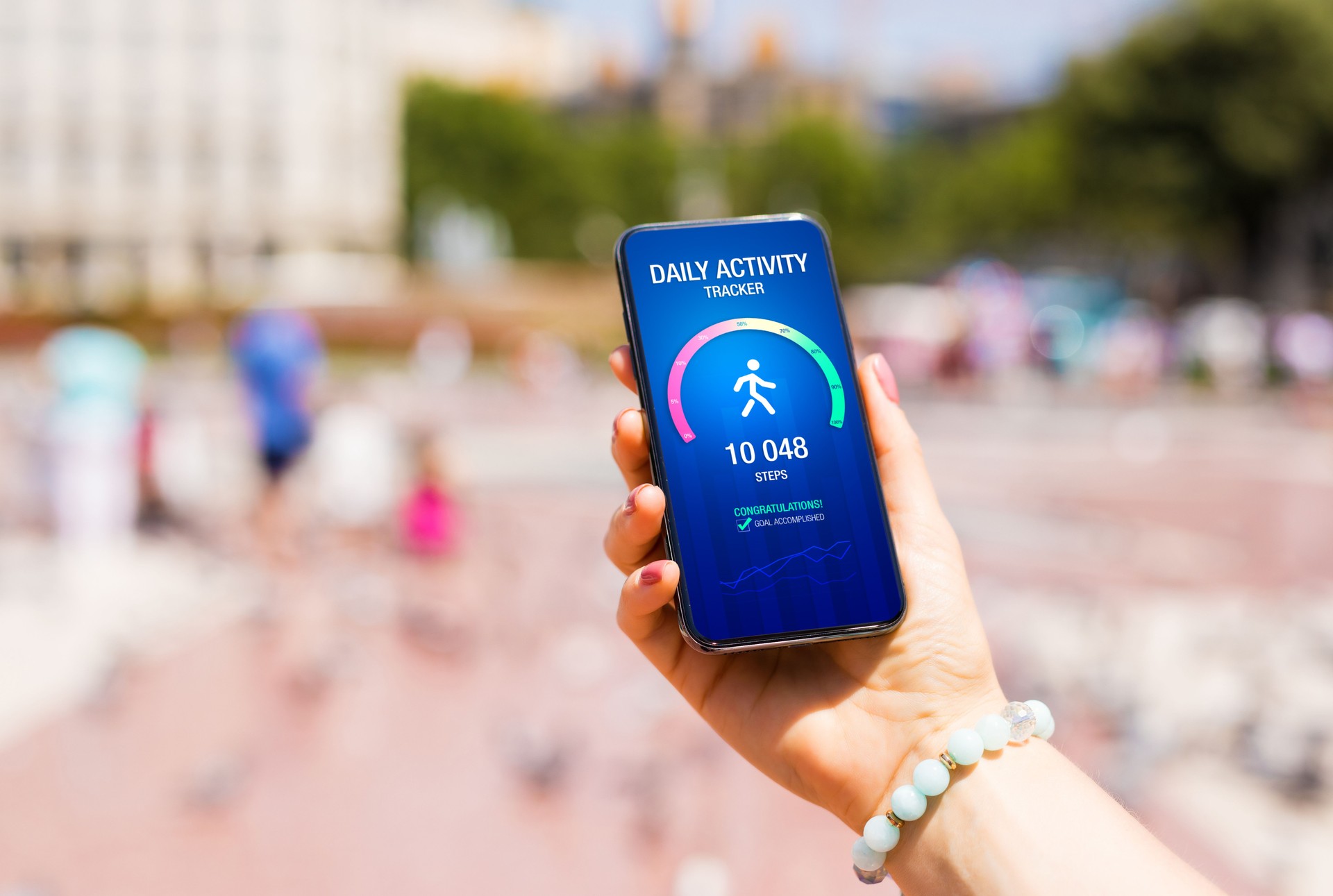 Woman using app on phone showing 10 000 steps goal achievement